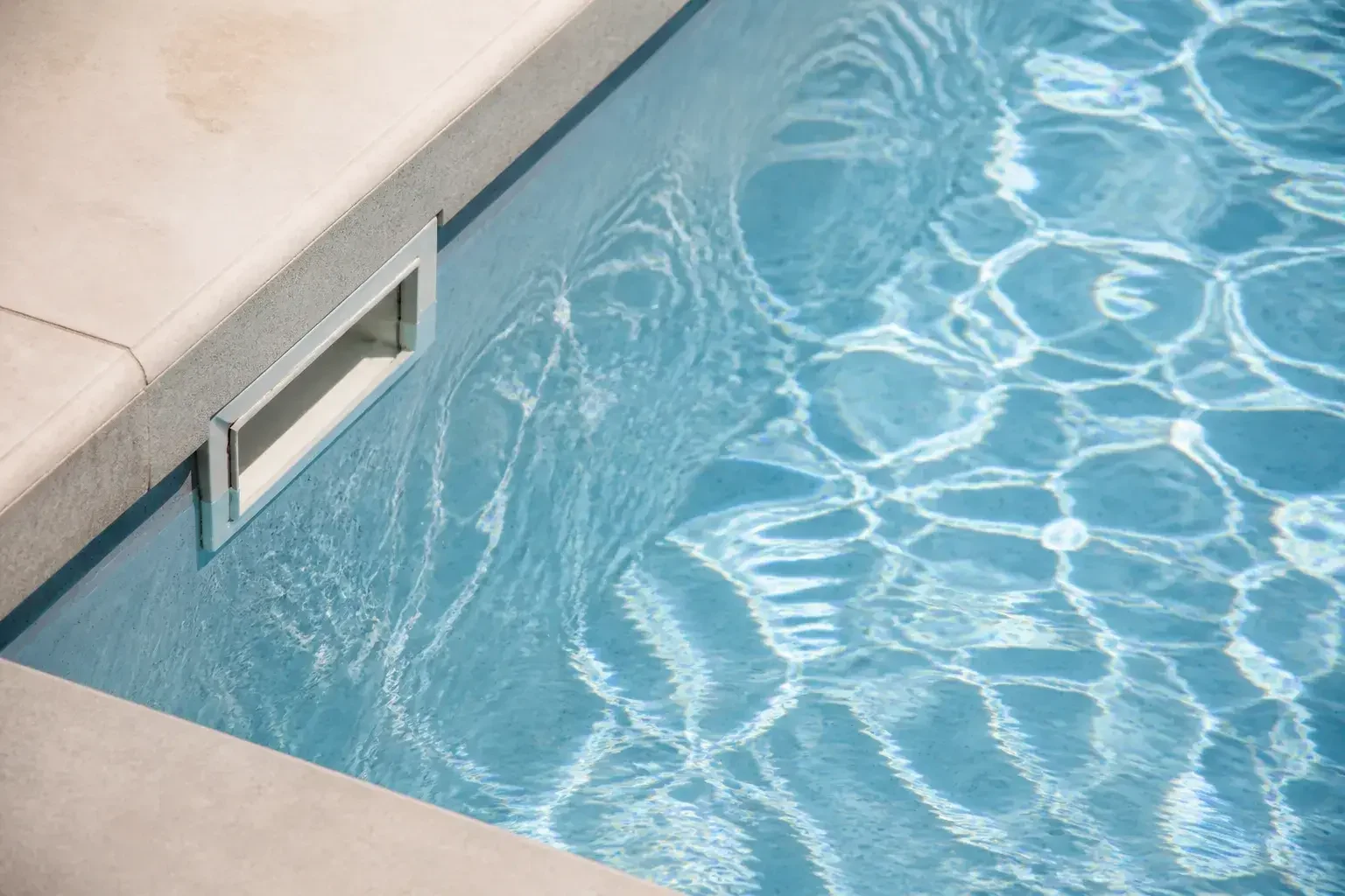 Detail eines sauberen Poolrands mit klarem Wasser.